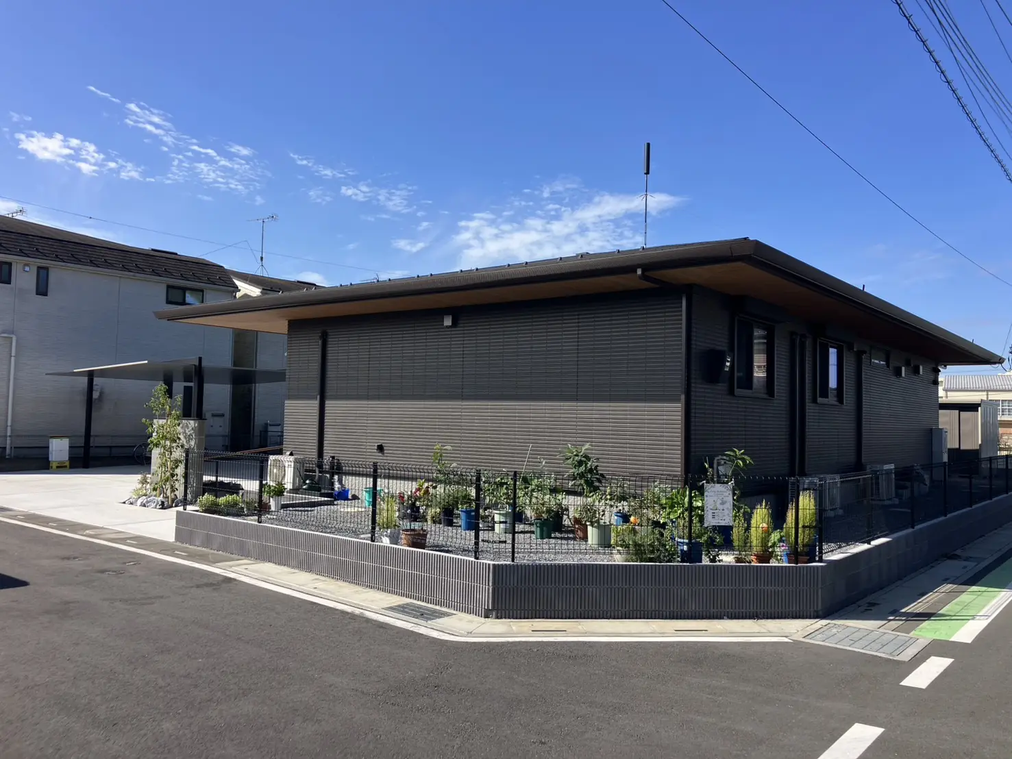 完成した平屋の外構。角地に沿って化粧ブロックとメッシュフェンス、奥にカーポート
