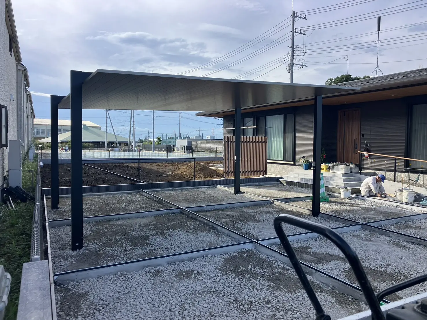 工事中。カーポートを建て、駐車場の土間コンクリートの下地をつくっているところ